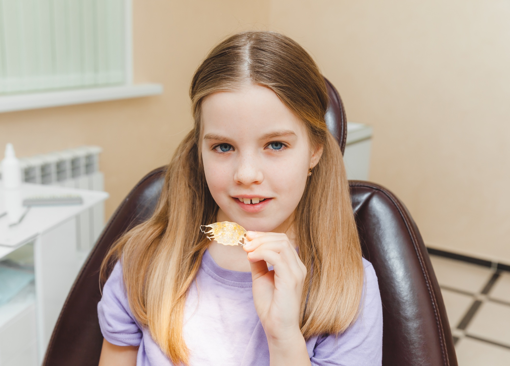 Dental plate. Expansion of the jaw in a child. teenage girl holding an orthodontic plate