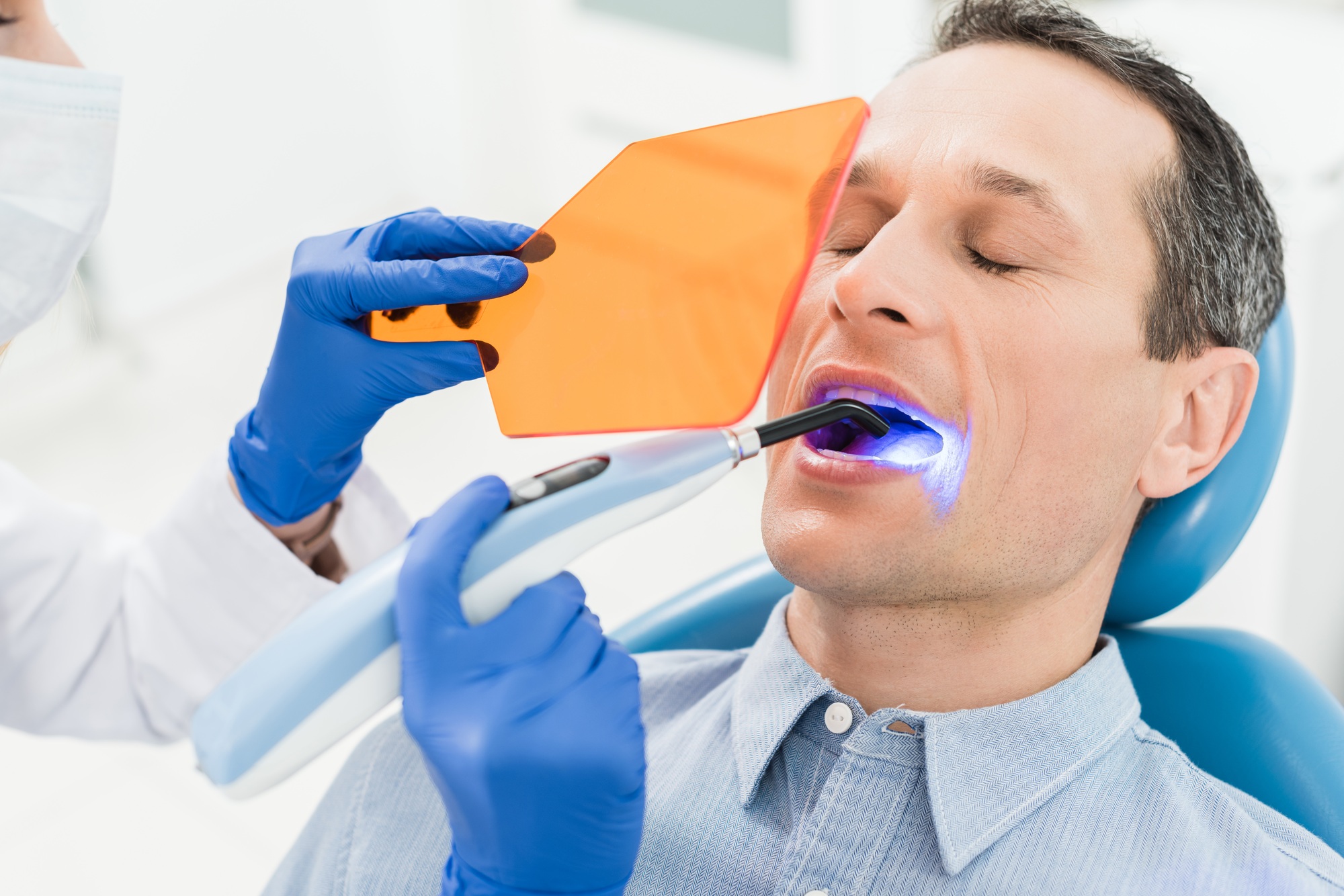 Male patient at dental procedure using uv lamp in modern dental clinic
